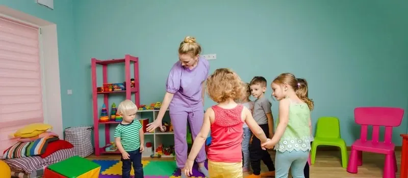 What Are Daycare Space Requirements Per Child? 1 A Caregiver Playing With Children In Mixed Age Rooms