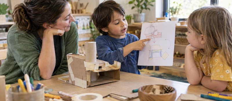 What Is A Makerspace? Understanding Making In Preschool 4 Preschool Child Explaining A Cardboard Prototype And Drawing To A Teacher